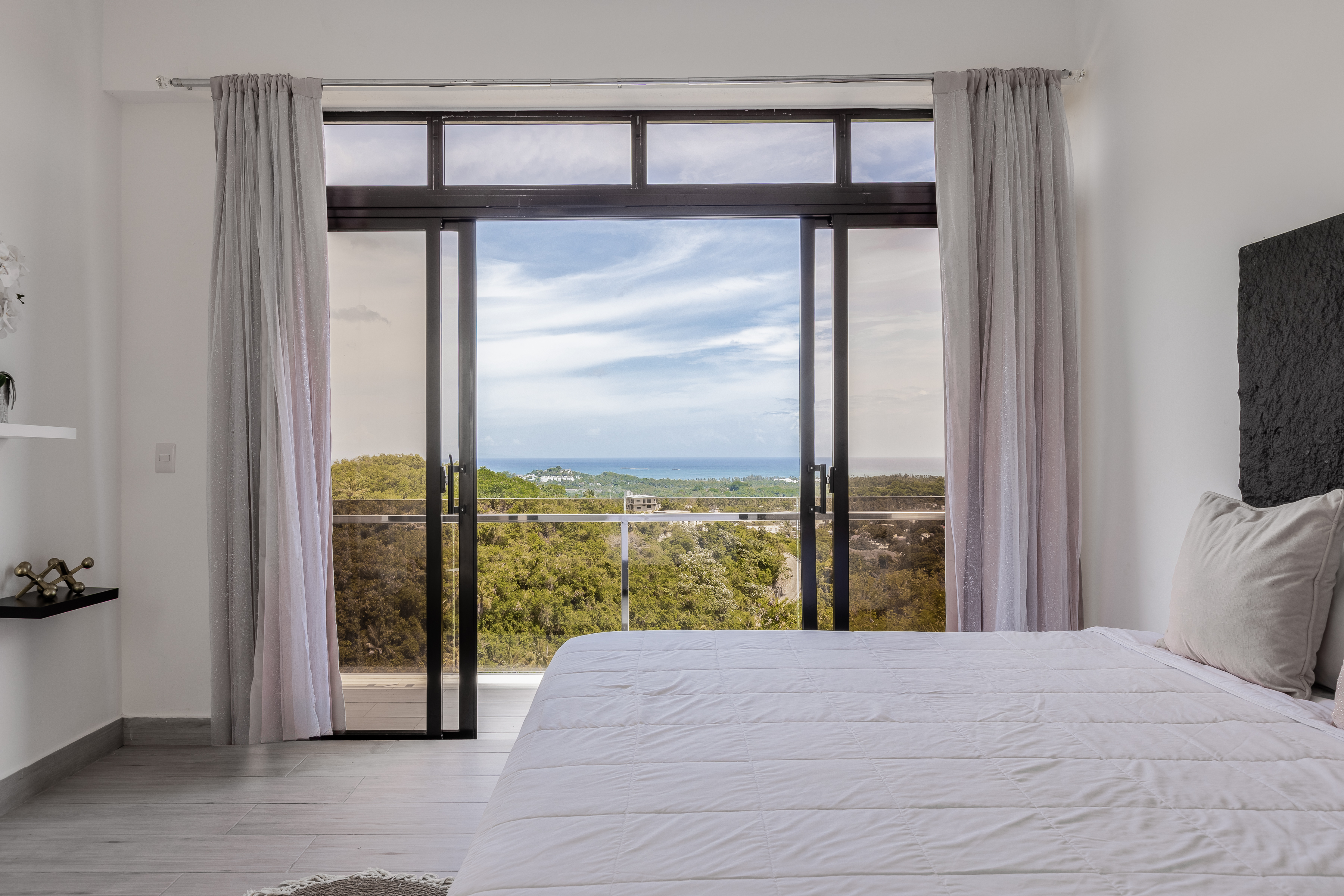 Bedroom view — sea and jungle through open floor-to-ceiling doors