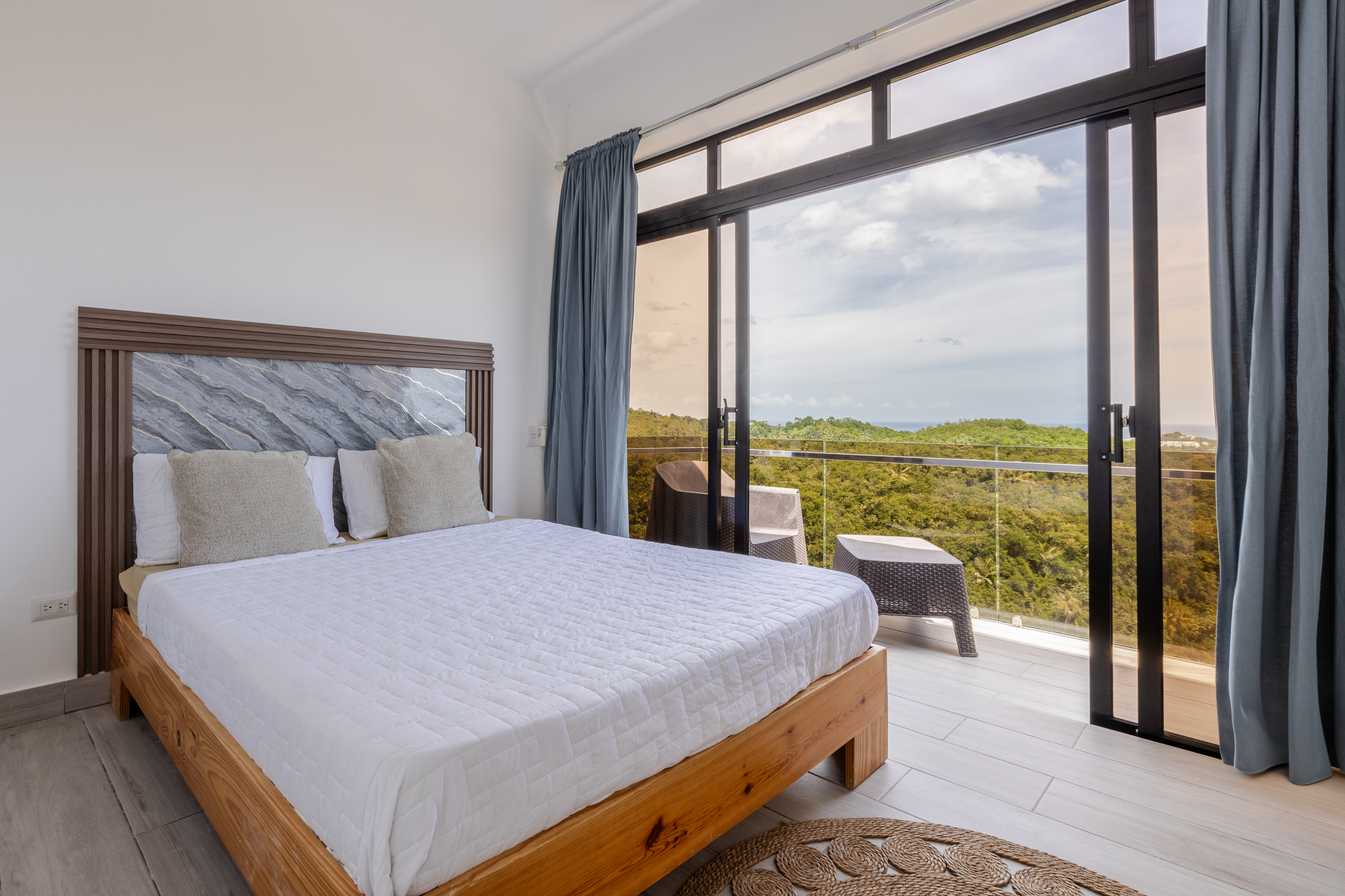 Bedroom with wood-frame bed and ocean view balcony