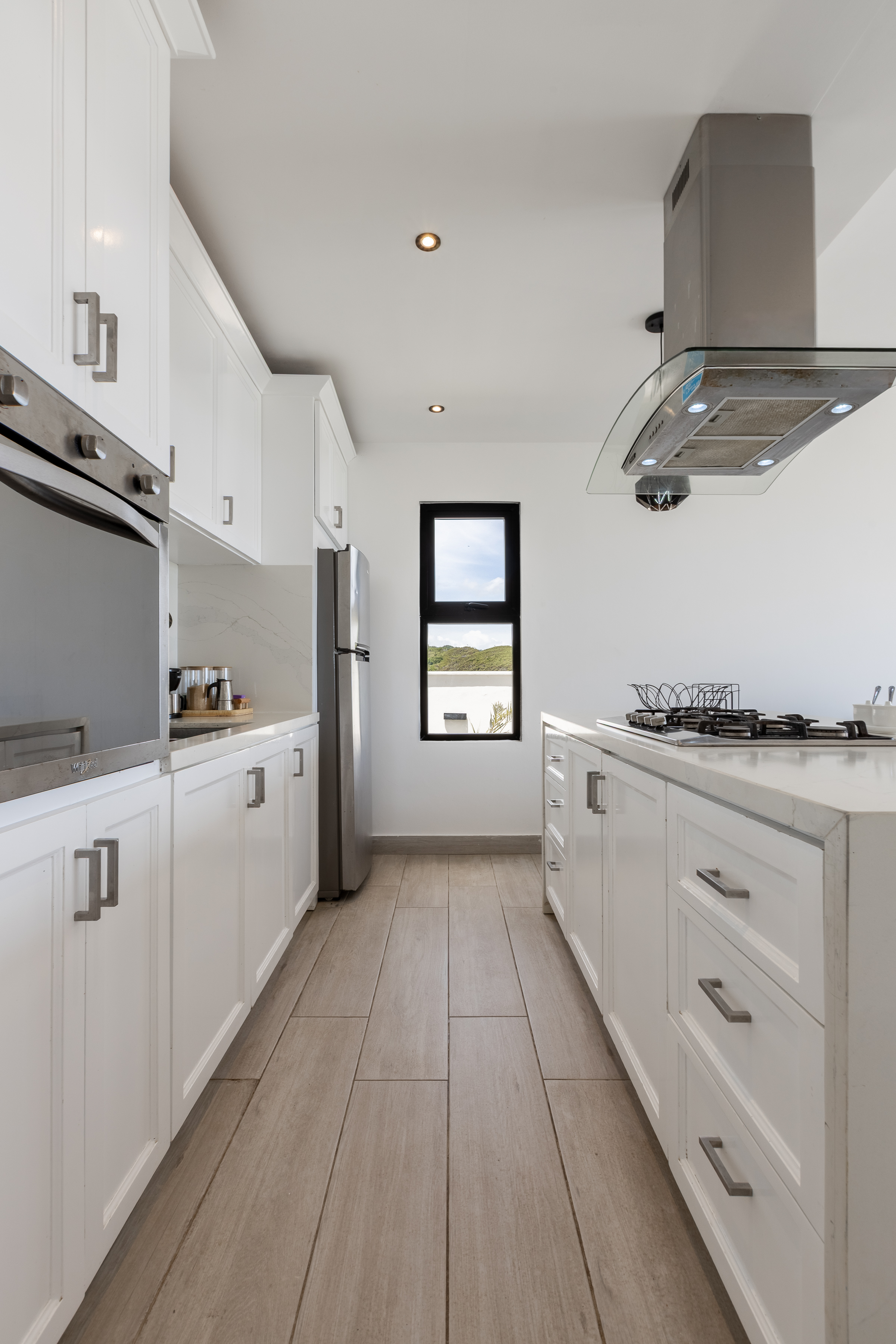 Full galley kitchen — floor-to-ceiling white cabinetry and pool glimpse